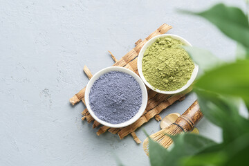 Bowls of different matcha tea powder and whisk on a concrete surface. Top view.