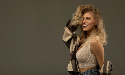 Close up of beautiful young woman with long blonde hair. Wears just beige bra and fashion stylish jeans.