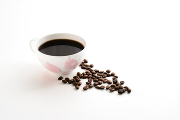 White cup of black coffee and sprinkled coffee beans nearby stock photo. Cup on a saucer of black coffee on white background