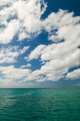 Deep ocean view with waves and white clouds. Relaxing seascape, endless sea, tropical waters background. Green seas and blue skies separated by a far away horizon. Caribbean lifestyle themes