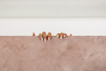 Beauty girl hands with pink and white manicure on the edge of a pink background