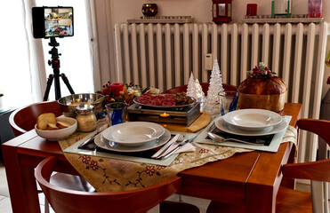 Christmas holidays table with tablet on tripod to enjoy distant communication with family during the Covid-19 pandemic. Protect infection from Coronavirus concept.