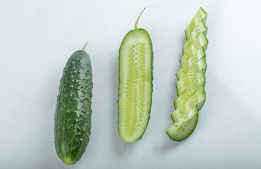 Close-up of whole fresh green cucumbers and slices isolated on white background.