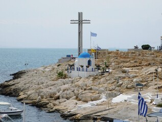 May 2018, Piraeus, Greece. View of the coast with ancient walls, church, and cross