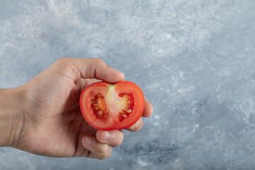 Man hands holding slice of red tomato
