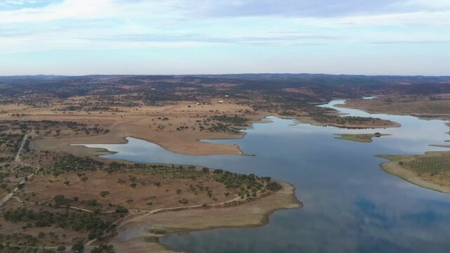 Drone aerial panorama of a dam lake reservoir landscape with olive and cork trees in Alentejo Terena, Portugal