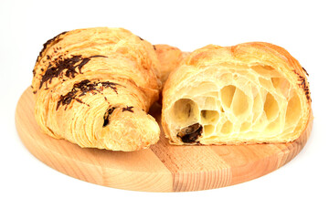 Croissants in chocolate sprinkles and with chocolate filling lying on a cutting board isolated on a white background
