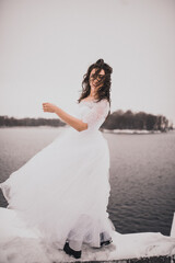 Fototapeta na wymiar girl brunette bride in a wedding dress in winter my in snow