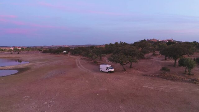 Drone aerial view of Camper van on an Alentejo dam lake landscape and under the shade of olive and cork trees, in Portugal