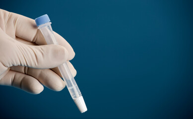 Laboratory scientist with vial and swab indoors performing a rapid diagnostic test, for antibodies, detecting the presence of viral proteins (antigens) expressed by corona virus disease COVID-19.blue