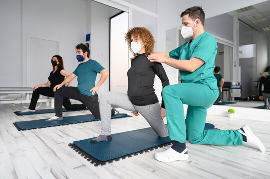 Group of persons on yoga mats assisted by physiotherapist at the rehabilitation clinic. High quality photo