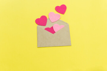 paper envelope with five pink hearts on a yellow background. valentine day concept. color of the year 2021