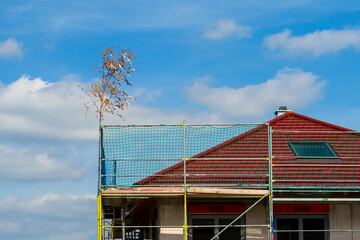 Symbolic branch on the house under construction, blue sky clouds in background