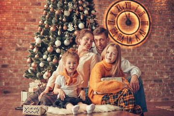 happy family sitting near Christmas tree in cozy living room