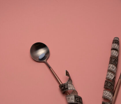 diet pills in a spoon. spiral measuring tape. fasting concept. space for text. Healthy lifestyle - Vitamins, minerals and nutritional supplements
