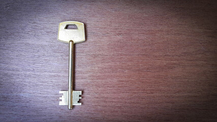 Large shiny vintage metal key on old wooden background