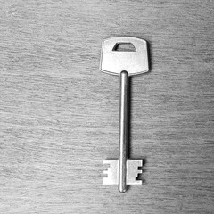 Large shiny vintage metal key on old wooden background