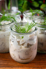 Pieces of herring in yoghurt with dill served in small jars.