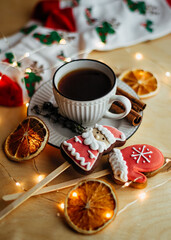 Cozy New Year still life. Cup of tea, dried orange, cookies in shapes of Santa and Mitten on wooden table. holidays, christmas, winter and drinks concept. Space for text.