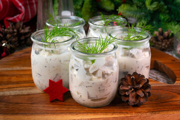 Pieces of herring in yoghurt with dill served in small jars.