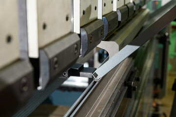 worker operating metal press machine at workshop.