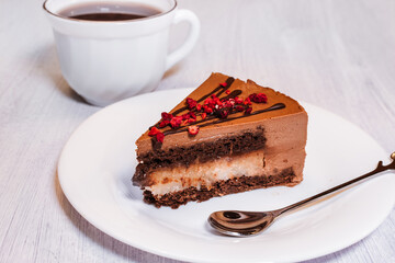 Chocolate cheesecake with chocolate glaze on white plate and light background