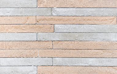 Texture of a rough stone wall made of gray and beige rectangular blocks.