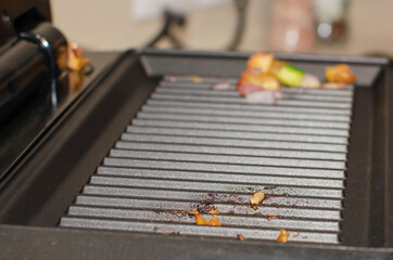 Electric grill after roasting meat. Oily greasy surface of the electric grill. Close-up