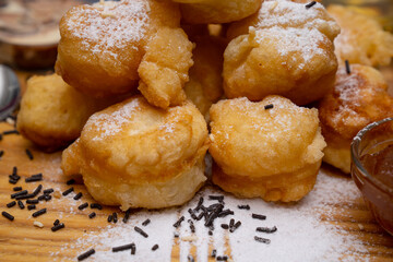 Sweet donuts with honey and chocolate cream. Cooked and served on wooden plate. They are sprinkled with powdered sugar.