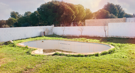 Fototapeta premium Old abandoned swimming pool overgrown with grass in the village