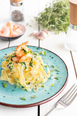 Italian pasta fettuccine in a creamy sauce with shrimp and spinach on a plate