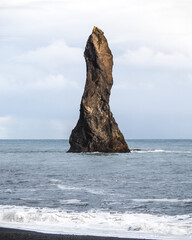 High pointy rock on the Icelandic shore, at the black sand beach of Vik, Iceland