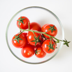 Cherry tomato in a transparent bowl on a white background