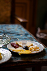Close up. White plate with different types of cheese, salami and figs cut into thin slices on the dining table. Traditional Italian appetizer in Palermo, Sicily, Italy. European cuisine