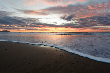 Golden sunrise across the ocean on a beach - 401572925