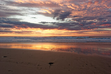 Golden sunrise across the ocean on a beach - 401573159