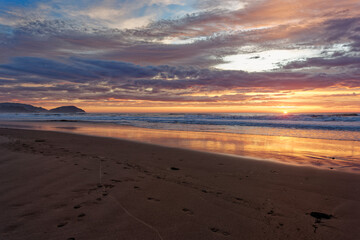 Golden sunrise across the ocean on a beach - 401573325