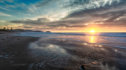 Golden sunrise across the ocean on a beach - 401573351