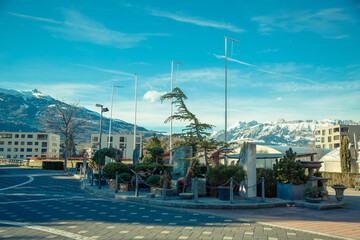 Alps mountains in Liechtenstein. Medieval House and vineyards in the capital of Liechtenstein in the city of Vaduz on the background of residential buildings, blue sky and snow-capped mountains 