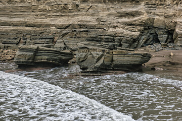 Waves pushing against a cliff eroded over time - 401573547