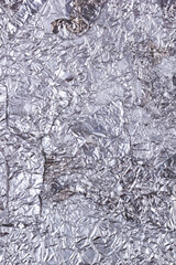 Shiny heavily wrinkled metal silver gray foil vertical texture background for design
