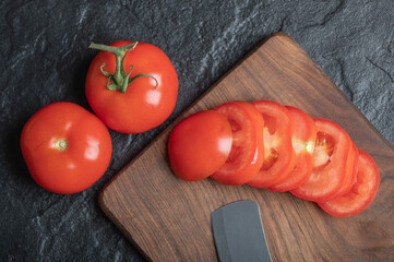 Close up view of freshly picked, juicy tomatoes on dark stone background