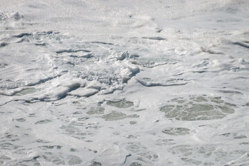White foam from surf on water surface .