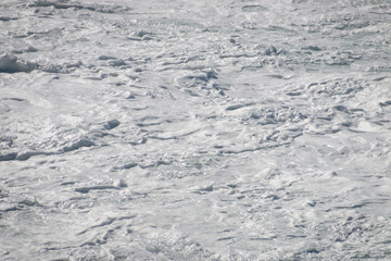 White foam from surf on water surface .