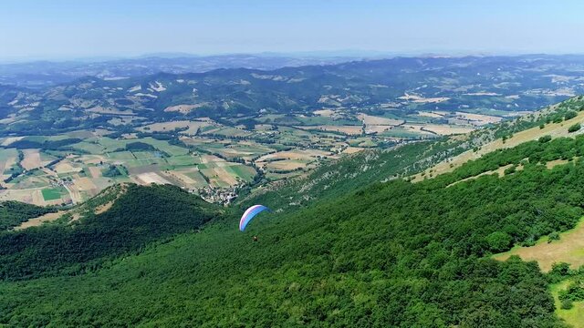 Aerial drone view during a paragliding flight from a mountain, breathtaking panorama. It feels like walking on the tip of the mountains, fun and adrenaline while flying