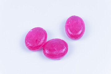 Three caramels of the same pink color on a white background