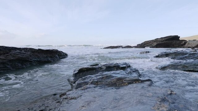 A large wave rushes toward the camera though stunning coastline.