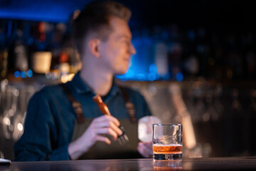 bartender preparing traditional old fashioned cocktail with whiskey and orange