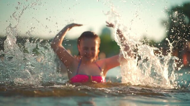 active young kid swim in lake, river or sea and play water splash at vacation