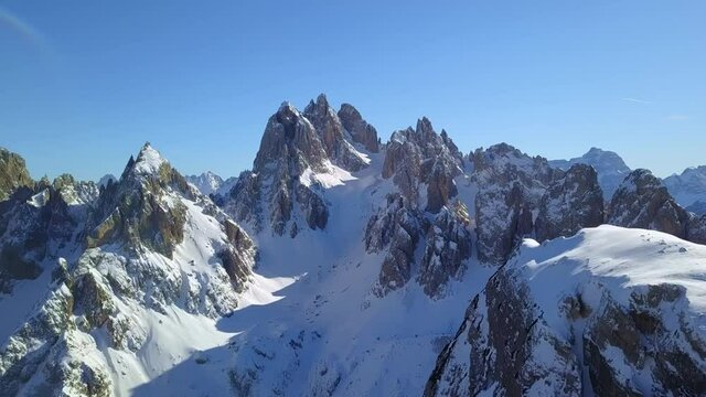 Daytime landscape of snow-capped mountain peaks of Dolomites in Italy, Europe. In a sunny winter day, a drone shooting and slowly advancing to the steep Dolomites